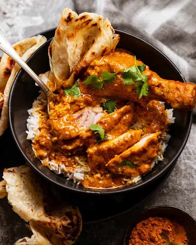 Butter chicken masala served over rice with naan